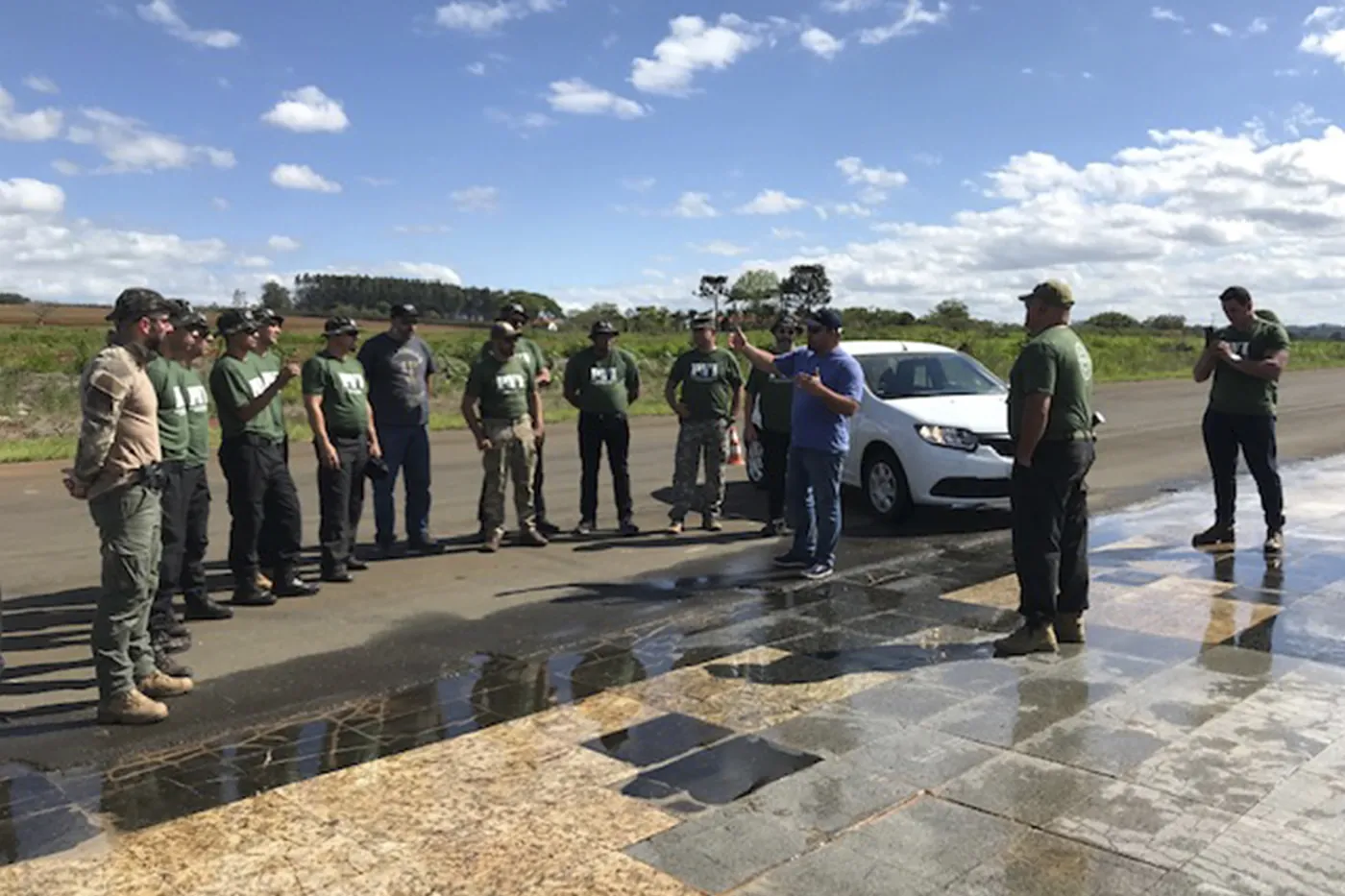 Equipe de motoristas reunida com o instrutor em pista molhada