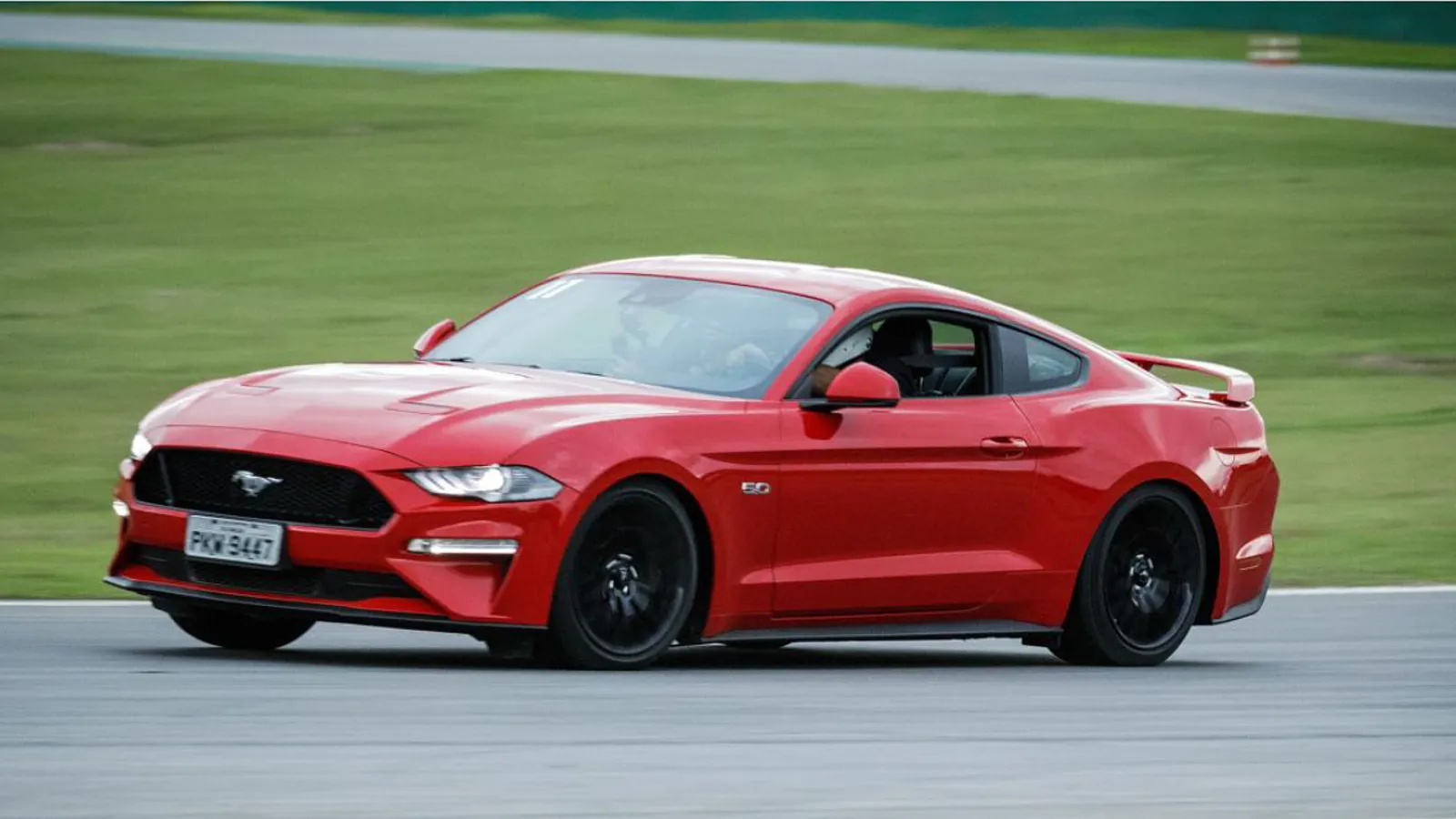 Carro esportivo em curva de autódromo durante sessão de coaching de pilotagem