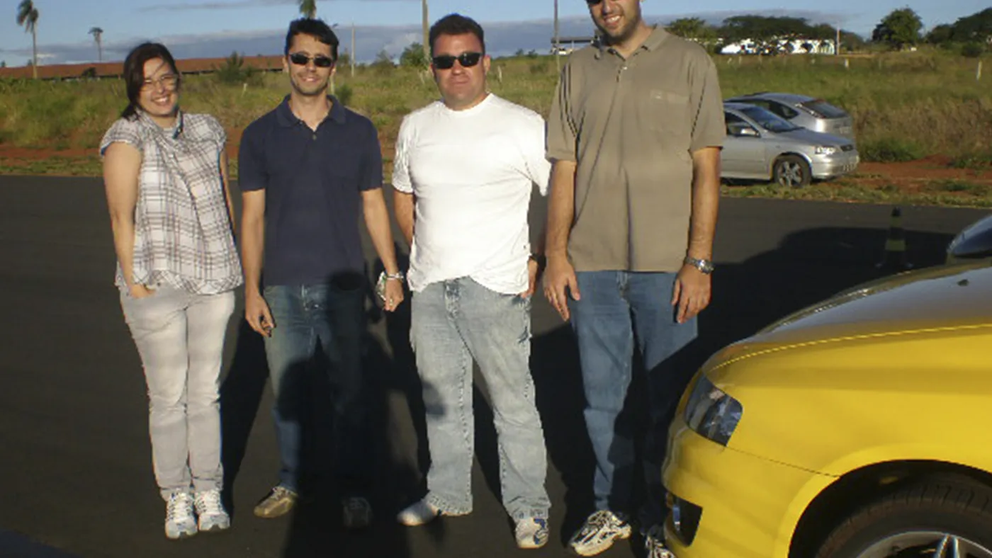 Equipe de motoristas reunida com o instrutor durante treinamento corporativo em pista